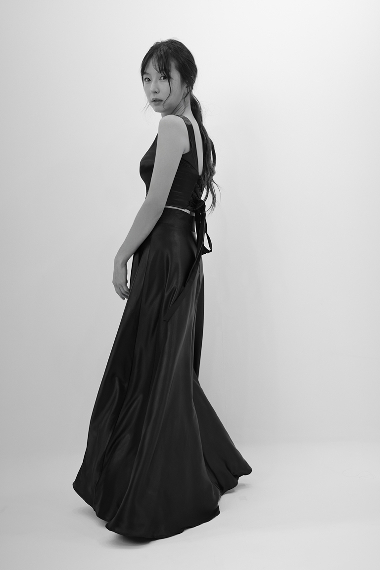 흑백 사진, 등을 끈으로 묶은 검은색 투피스 드레스를 입은 모델